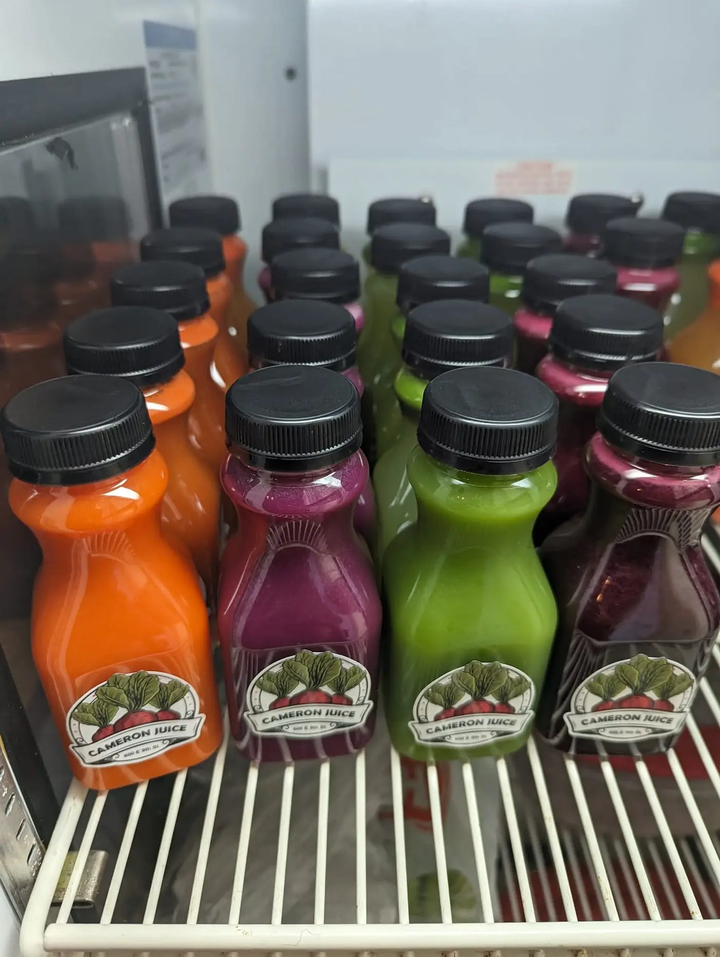 Cameron Juice bottles with the leaf logo in carrot-orange, beet-purple and green