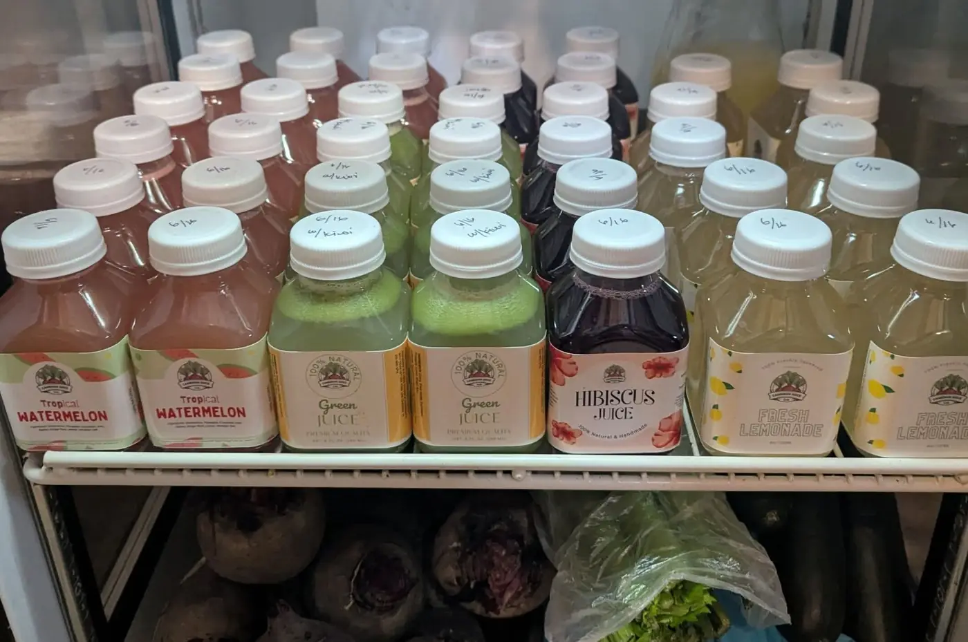 Cameron Juice bottles lined up in the cooler — Tropical Watermelon, Green Juice, Hibiscus and Fresh Lemonade