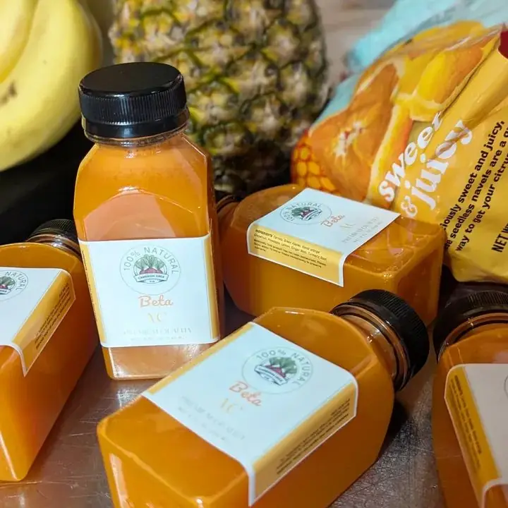 Close-up of Cameron Juice Beta bottles with fresh pineapple and oranges