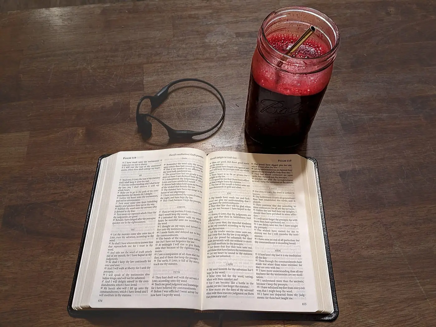 A jar of Cameron Juice beside an open Bible on a wooden table